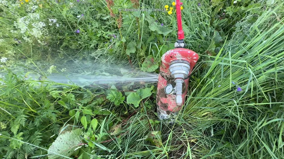 Borne hydrante rouge présentant une projection d’eau sur le côté